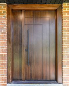 a brown wooden door with brick pillars and an iron handle on the outside of it