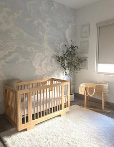 a baby's room with a crib, chair and potted plant