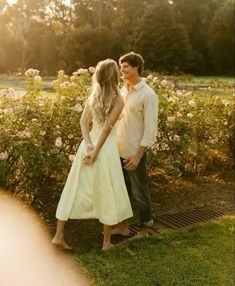 a man and woman standing next to each other in front of flowers