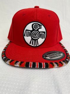 You are viewing a hand-beaded baseball hat with thunderbird patch. The red hat is ADULT size. All beads are sewn by hand.  All patches are applied by hand. No two hats are exactly alike and will never be replicated exactly. Made by an indigenous artist, I am an enrolled member of the Jumano Nation of West Texas. Free shipping to US locations only Traditional Adjustable Snapback Baseball Cap, Traditional Adjustable Snapback Hat, Red Beaded Festival Hat, Red Embroidered Snapback Hat, Red Embroidered Snapback Trucker Hat, Red Trucker Hat For Festival, Red Adjustable Hats With Flat Crown, Adjustable Red Hats With Flat Crown, Adjustable Red Hat With Flat Crown