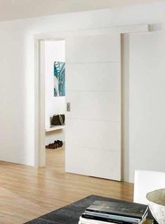 a living room with hard wood floors and white walls on the wall is an open door