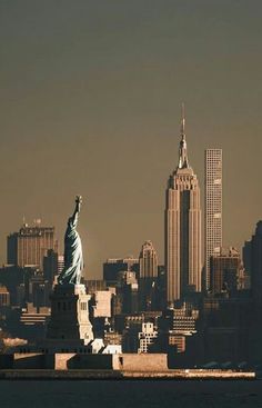 the statue of liberty stands in front of the new york city skyline