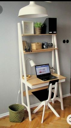 a laptop computer sitting on top of a wooden desk next to a shelf with shelves