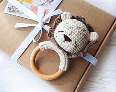 a crocheted lion head on top of a cardboard box with a wooden ring