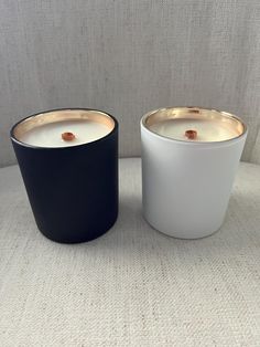 two black and white candles sitting next to each other on top of a cloth covered table