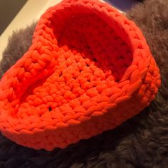 an orange crocheted basket sitting on top of a furry animal's fur