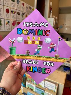 someone is holding up a purple graduation cap that says it's me doing ready for kinder