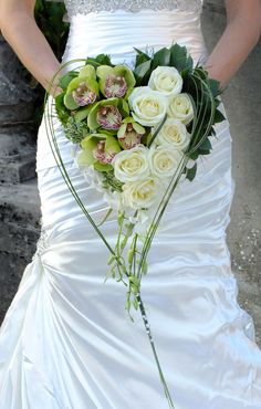 a bride holding a bouquet of white roses and orchids