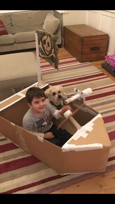 a boy and his dog are in a cardboard boat