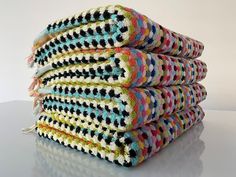 stack of multicolored crocheted towels sitting on top of each other in front of a white background