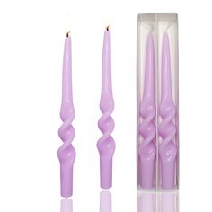 two purple candles in a box with one candle on the other side and an odd shaped object next to it