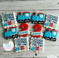 decorated cookies with trains and numbers for two birthdays on a white wooden table top