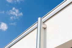 the corner of a white building with a blue sky in the backgrounnd