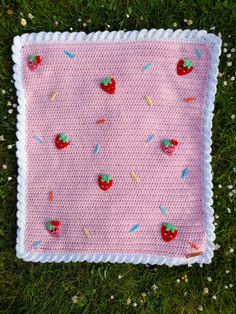 a crocheted pink blanket with strawberries and sprinkles on it