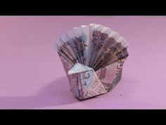 an origami fan made out of money on a pink background