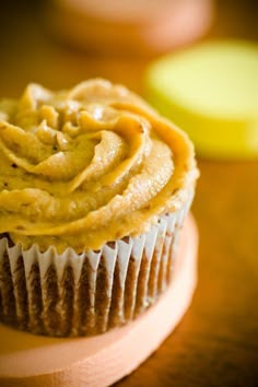 a cupcake sitting on top of a wooden table next to an orange and yellow apple