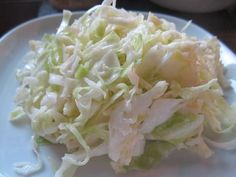 a white plate topped with coleslaw on top of a table