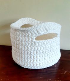 a white crocheted basket sitting on top of a wooden table