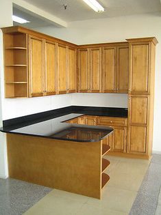 an empty kitchen with wooden cabinets and black counter tops