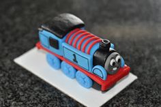 a toy thomas the train is sitting on top of a white plate with black and red trim