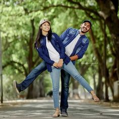 a man and woman are holding each other in the middle of an empty street with trees behind them