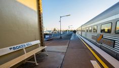 a bench sitting next to a train on the tracks