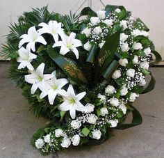 white flowers and greenery are arranged in a heart - shaped arrangement on the sidewalk