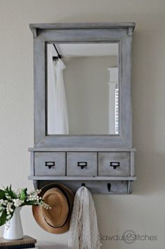 a mirror sitting on top of a wooden shelf next to a vase with flowers in it