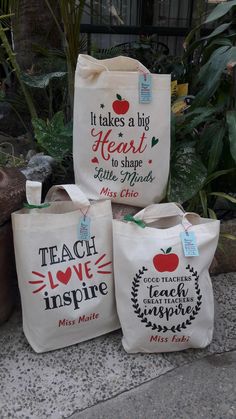 three bags with different designs on them sitting next to each other in front of some plants