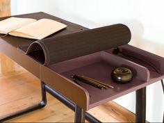 a desk with a book, pen and notebook on it in front of a wall