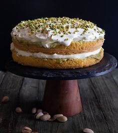 a cake with white frosting and pistachio sprinkles on top