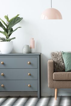 a living room with a couch, dresser and potted plant on the side table