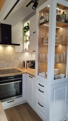 a kitchen with an oven, sink and glass shelves on the wall above the stove