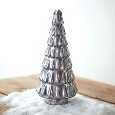 a small silver christmas tree sitting on top of snow