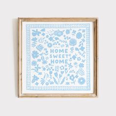 a blue and white framed print with the words home sweet home in floral designs on it