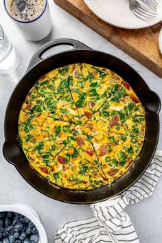 an omelet with spinach and cheese in a pan next to blueberries