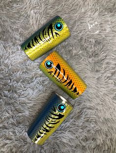 three cans with eyes painted on them sitting on a carpeted floor next to each other