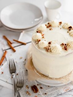 a white cake sitting on top of a table next to silverware and utensils