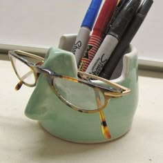 a cup that has some pens and glasses in it