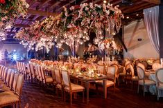 a dining room filled with lots of tables covered in white linens and floral centerpieces