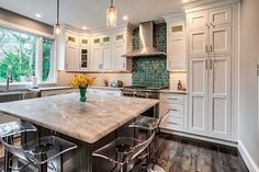 a large kitchen with an island in the middle and two bar stools at the end