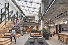 an office lobby with stairs, couches and people walking up the stairs to the second floor