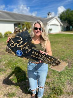 a woman holding up a sign that says marilyn marques in front of her house