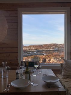 the table is set for two with wine glasses, plates and utensils on it