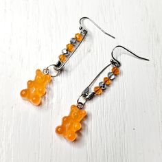 a pair of earrings made out of glass beads and silver hooks on a white wooden surface