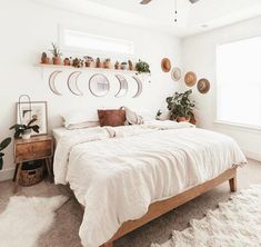 a bedroom with white walls and lots of potted plants on the shelves above the bed