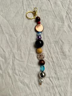 a keychain with several different colored beads and charms attached to it on a white sheet