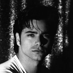 a black and white photo of a man in front of sequin wallpapers