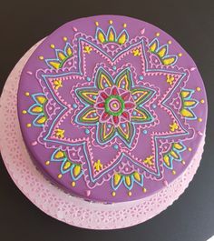 a cake decorated with an intricate design on top of a pink doily covered plate