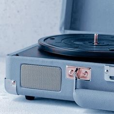 an old record player sitting on top of a blue suitcase with its lid open and the cover partially closed